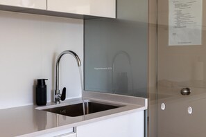 Eine moderne Küche mit Spülbecken aus Edelstahl, einer schwarzen Flasche und einer Glasrückwand.