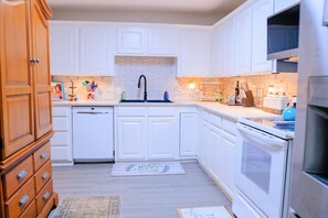 A kitchen with white cabinets, a dishwasher, a sink, and a stove. - Nanny`s Nest - A Gentle Place to Land (Nederland)