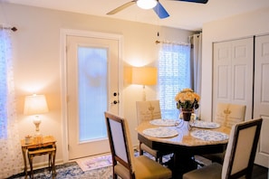 A dining area with a round table, chairs, a vase with flowers, and a lamp. - Nanny`s Nest - A Gentle Place to Land (Nederland)