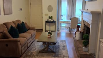 Un salon comprenant un canapé, une table basse, une cheminée, un téléviseur et un ventilateur de plafond.