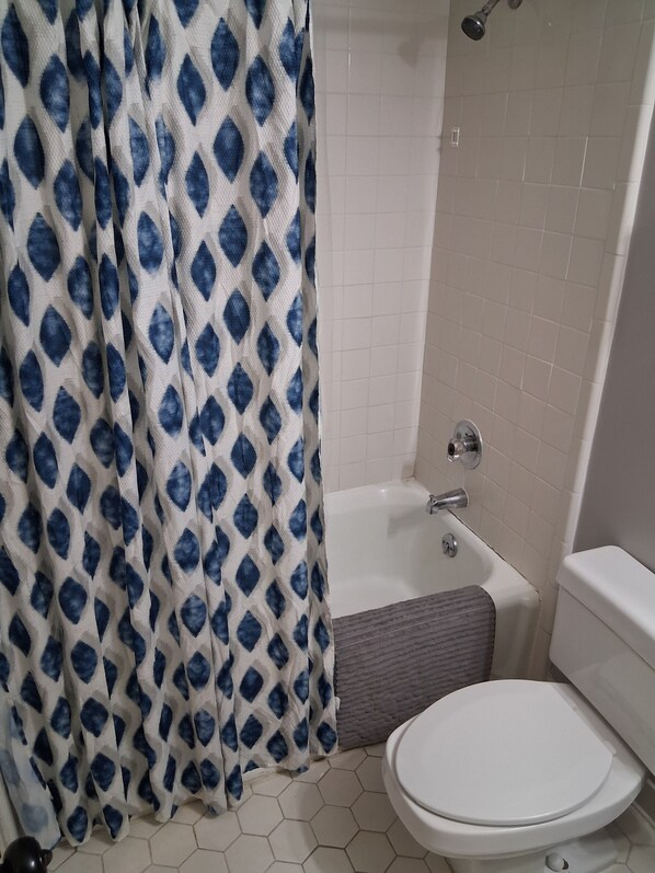 A bathroom with a white toilet, a bathtub, and a shower. - Hidden Gem Townhouse 2-bedroom Flat (Columbus)