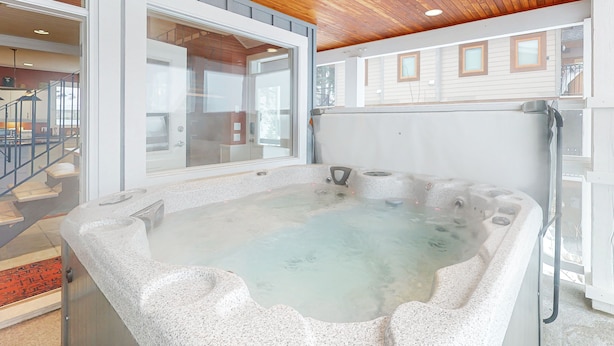Un jacuzzi en una habitación con techo de madera y ventanas amplias.