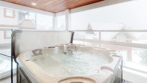 Un jacuzzi en una habitación con techo de madera y ventanas amplias.