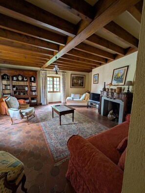 A spacious living room with a fireplace, a sofa, a coffee table, and a bookshelf.