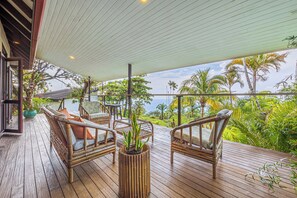 Eine Holzterrasse mit Korbmöbeln und einer Topfpflanze.