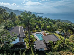 Ein tropisches Resort mit Swimmingpool, Palmen und Blick auf den Ozean.