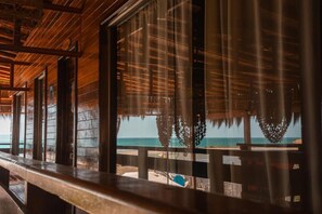 A wooden structure with large windows overlooking a beach.