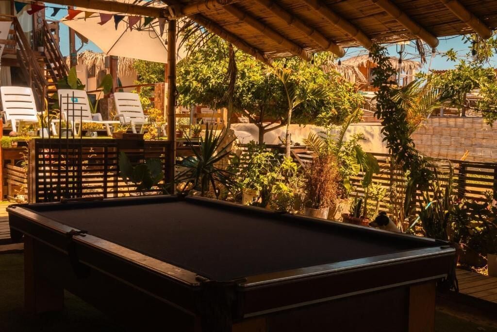 Een pooltafel in een buitenruimte met houten leuningen en plantenpotten.