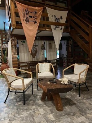 A rustic interior with wicker chairs, a wooden coffee table, and hanging banners.