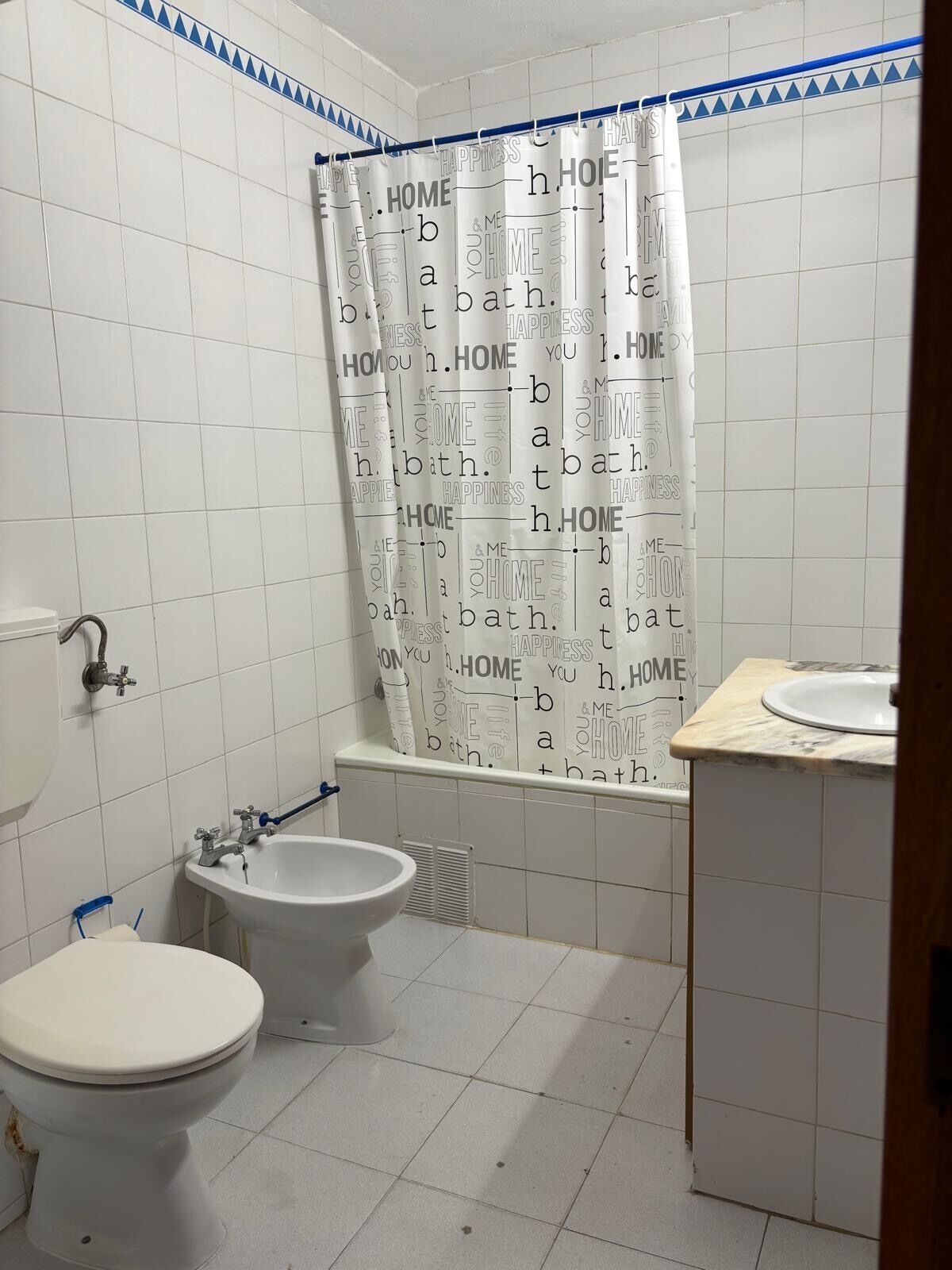 A bathroom with two toilets, a bathtub, and a sink.