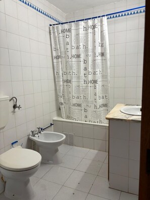 A bathroom with two toilets, a bathtub, and a sink. - 1-Bedroom Apartment in Praia da Rocha, Porimão (Portimão)