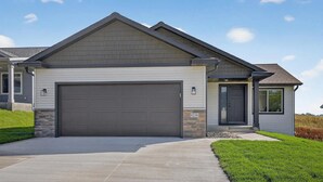A modern single-story house with a large garage, stone foundation, and a well-maintained lawn. - Perfect Luxury 4-bedroom house with Central AC in Rochester (Rochester)