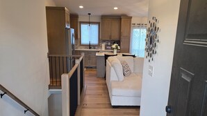 A modern kitchen with wooden cabinets, a central island, and a dining area with a white sofa. - Perfect Luxury 4-bedroom house with Central AC in Rochester (Rochester)