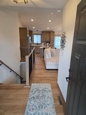 A modern kitchen with wooden cabinets, a central island, and a dining area with a white sofa. - Perfect Luxury 4-bedroom house with Central AC in Rochester (Rochester)
