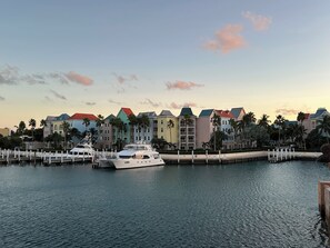 Eine Marina mit einer weißen Yacht an der Anlegestelle, bunte Gebäude im Hintergrund und eine ruhige Wasseroberfläche.