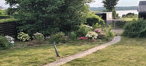 Ein Garten mit gepflastertem Weg, üppigem Grün und blühenden Pflanzen.