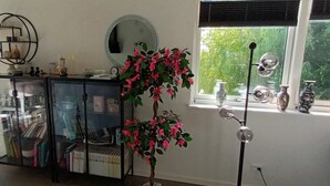 Quarto com um armário de vidro, um espelho, um vaso de planta e uma janela com vista para vegetação.