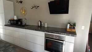 Cozinha moderna com forno embutido, pia, máquina de café e televisão de tela plana na parede.