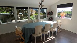 Uma sala de jantar com uma mesa redonda, seis cadeiras e grandes janelas com vista para o verde.