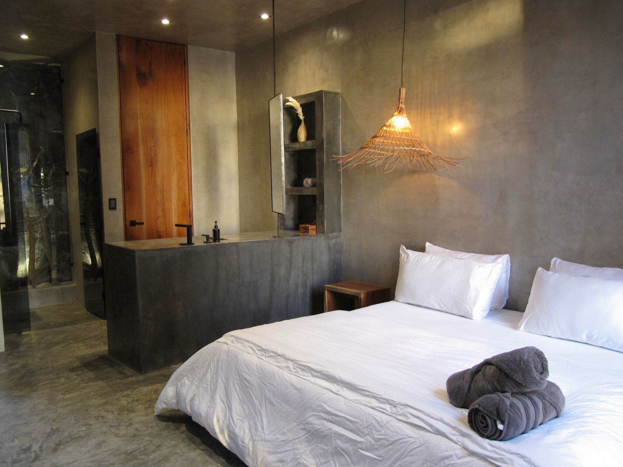 Un dormitorio moderno con una cama grande, un tocador integrado y una lámpara colgante original.