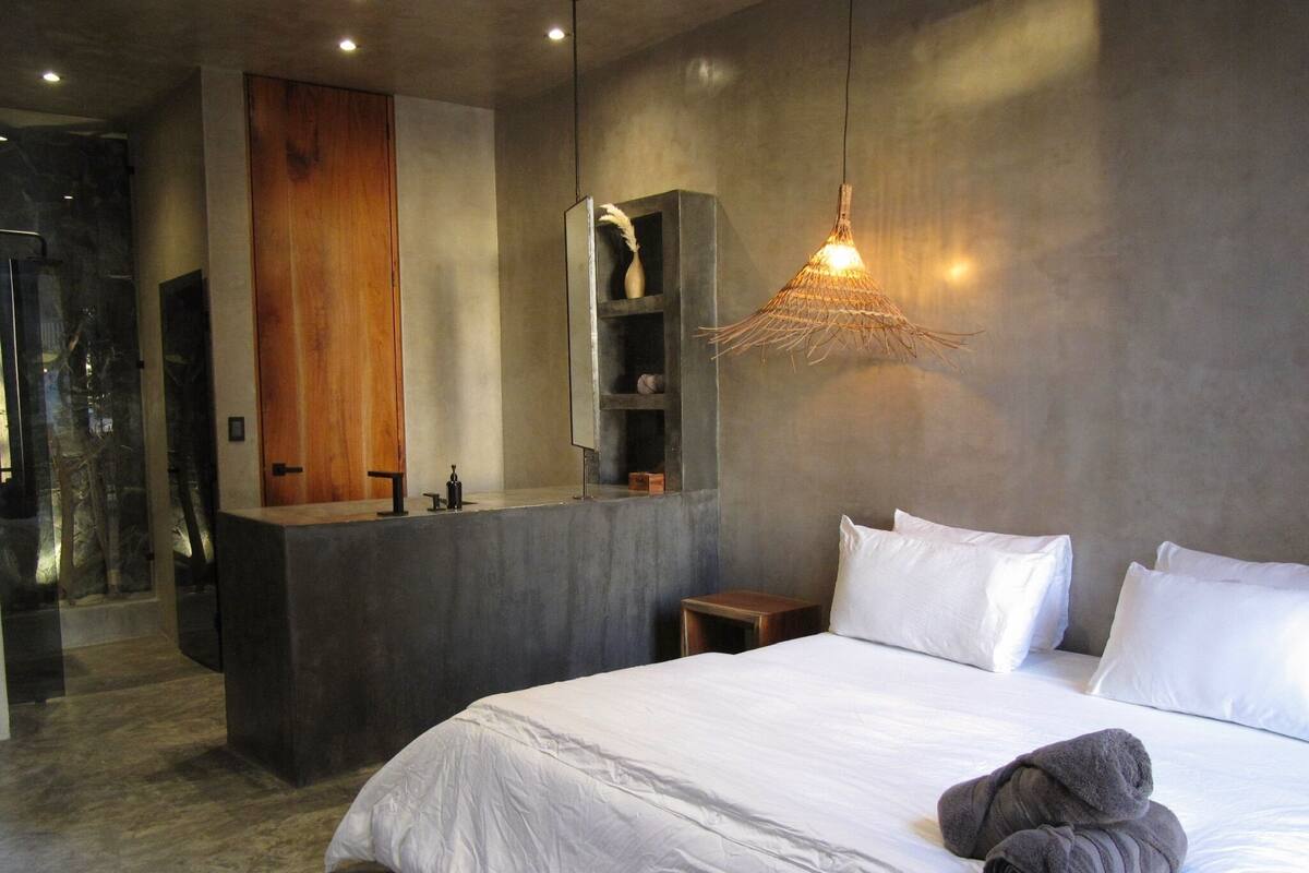 Un dormitorio moderno con una cama grande, un tocador integrado y una lámpara colgante original.