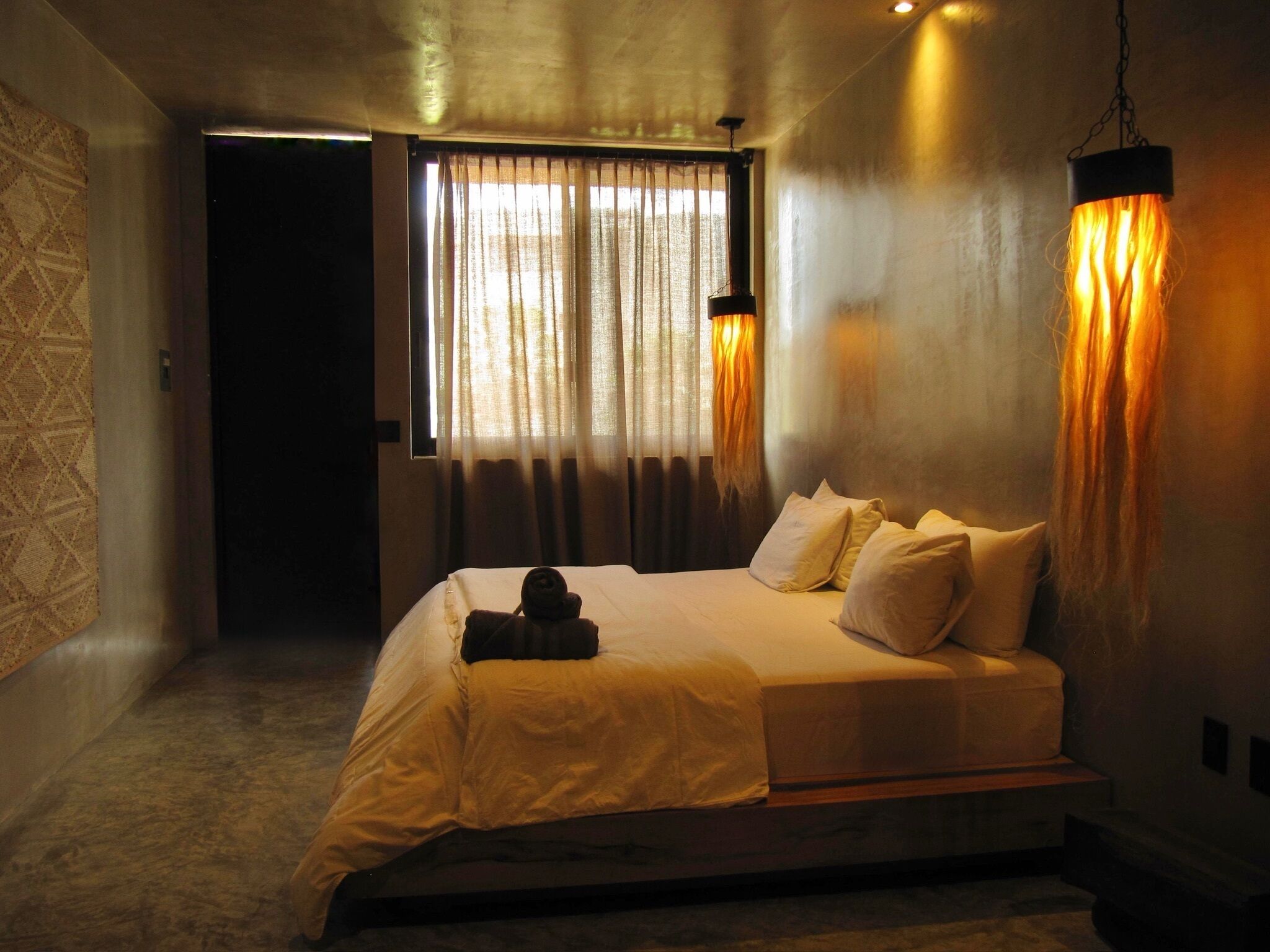 Un dormitorio con cama, cortinas y lámpara colgante.