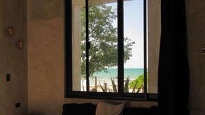 Una habitación con un ventanal grande, un sofá, una mesa de madera y vista a la playa.