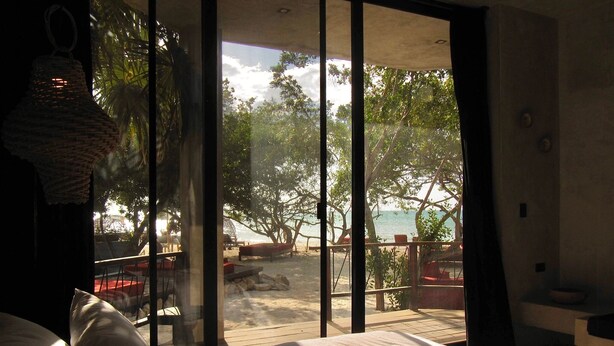 Un dormitorio con un ventanal grande con vistas a la playa.