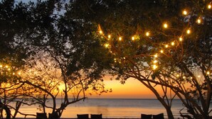 Una playa con luces colgantes, bancos y vistas al atardecer.