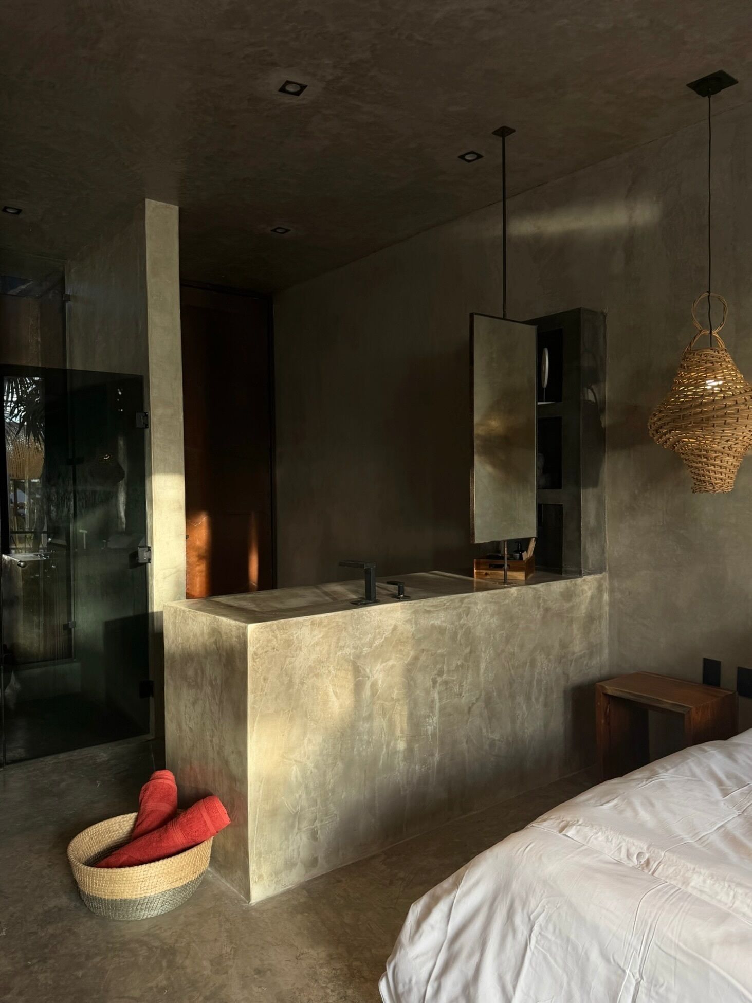 Un baño moderno con ducha de vidrio, un espejo grande y una lámpara colgante.
