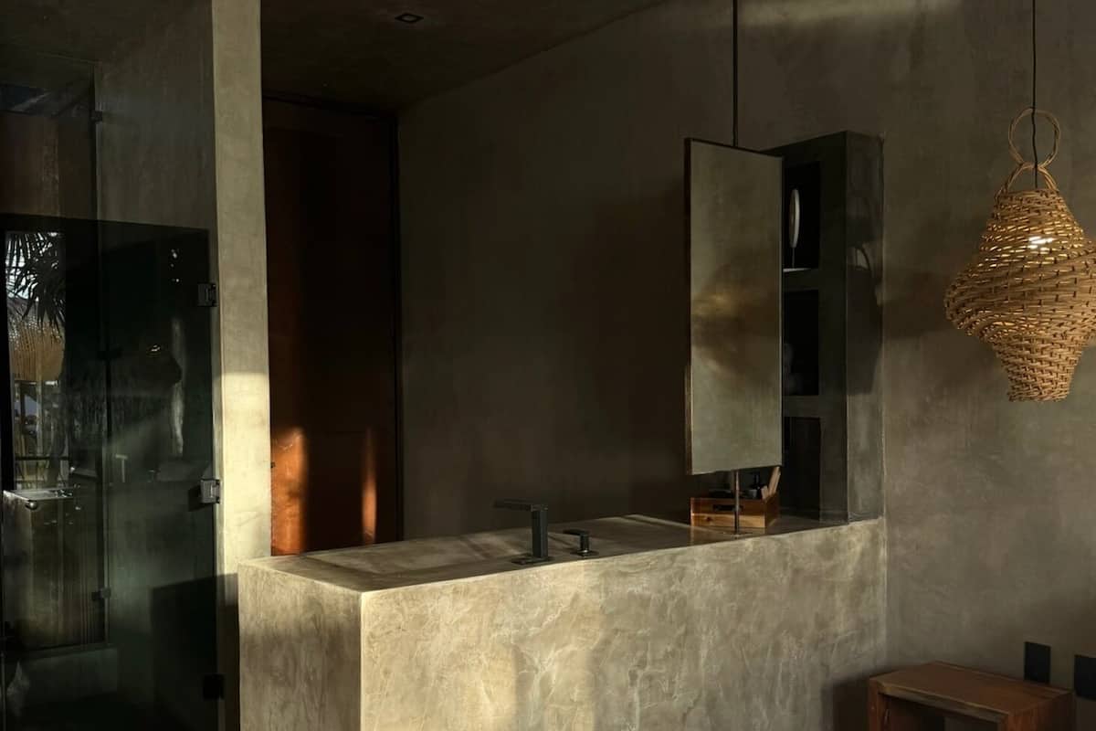 Un baño moderno con ducha de vidrio, un espejo grande y una lámpara colgante.