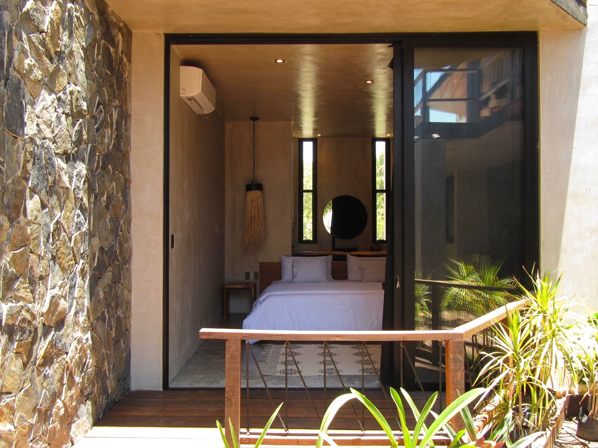 Un dormitorio con cama, una lámpara colgante y vistas a través de una puerta de cristal.