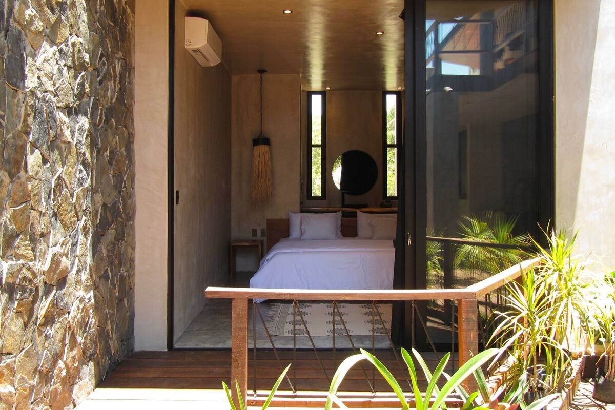 Un dormitorio con cama, una lámpara colgante y vistas a través de una puerta de cristal.