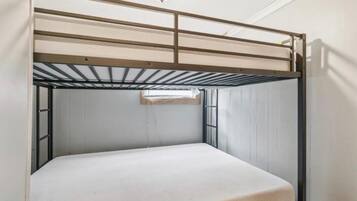 Un lit superposé avec un matelas, une structure en métal et un luminaire fixé au plafond.