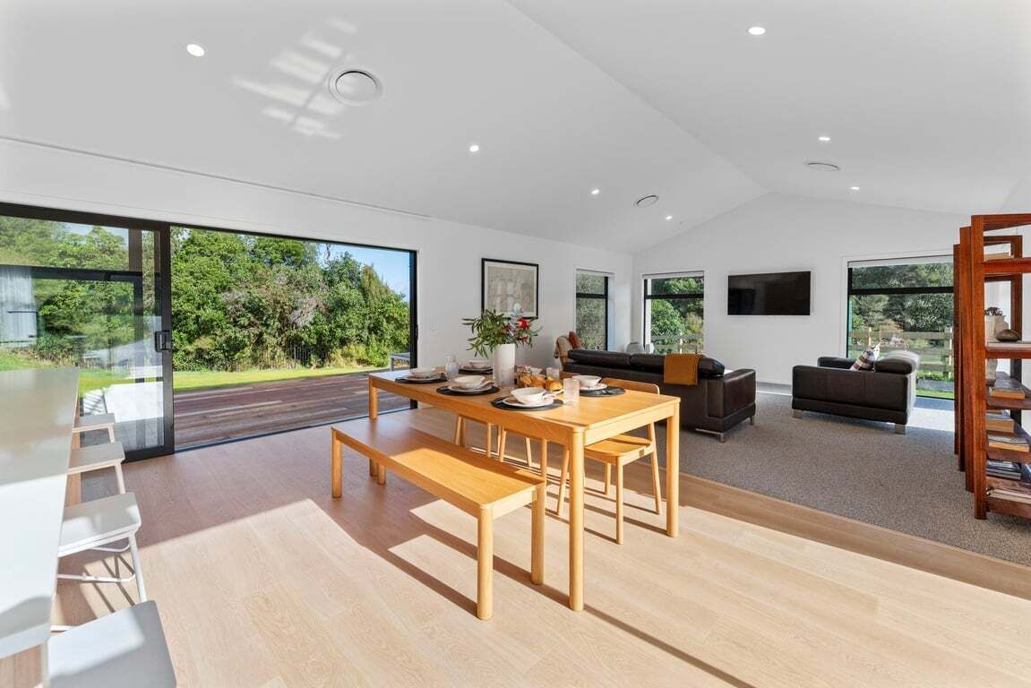 A modern interior with a dining area, sofas, and large windows.