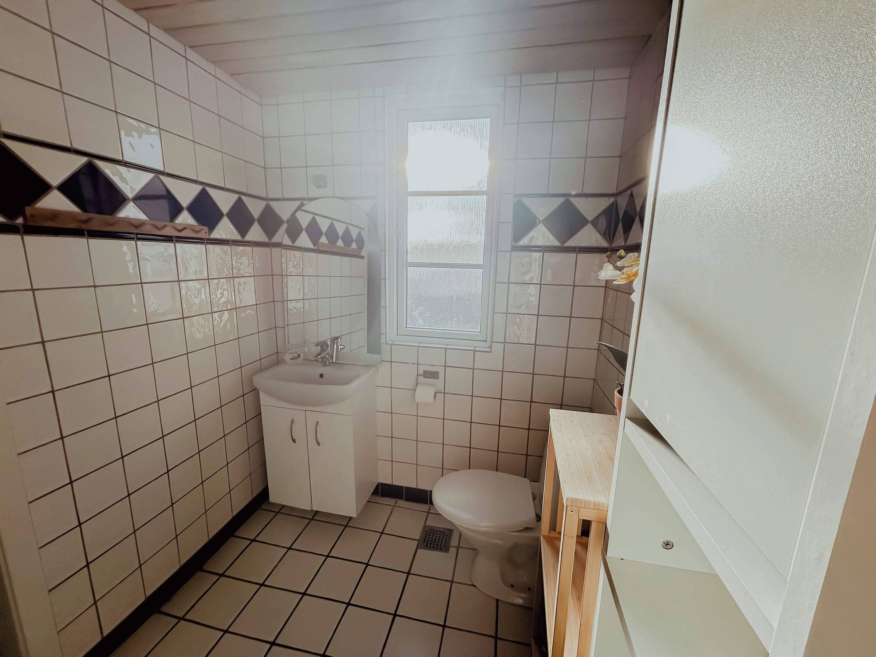 Une petite salle de bain avec un lavabo, des toilettes et une fenêtre.