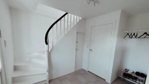 Un intérieur blanc avec un escalier, une porte et un porte-chaussures.