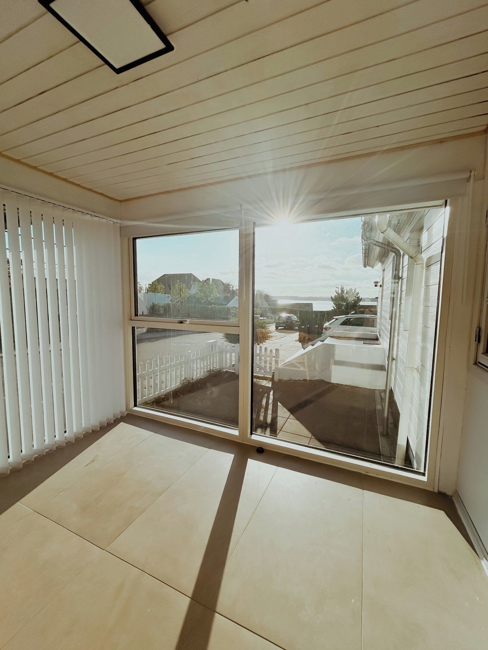 A room with a large sliding glass door, a white ceiling, and a tiled floor.