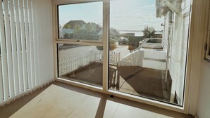 Une pièce dotée d’une grande porte-fenêtre coulissante, d’un plafond blanc et d’un sol carrelé.