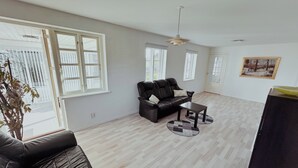 Un salon spacieux avec un canapé en cuir, une table basse et un tableau accroché au mur.