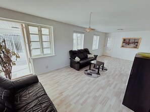 Uma sala de estar espaçosa com um sofá de couro, uma mesa de centro e um quadro na parede.