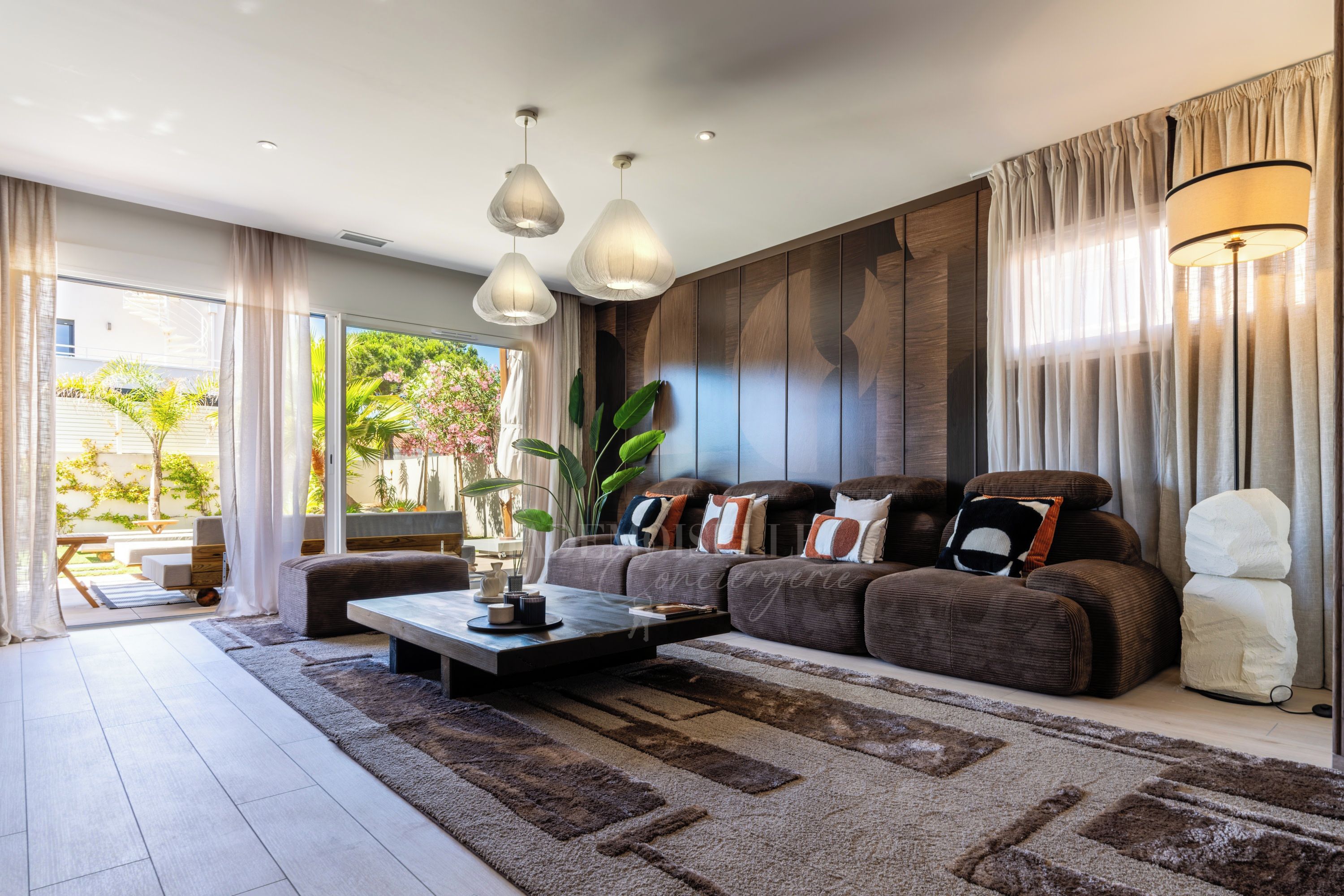 A modern living room with a sectional sofa, a coffee table, and a large window with curtains.
