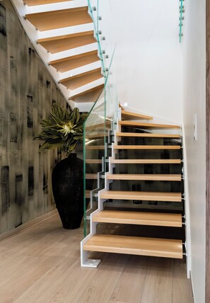 A modern staircase with glass railings and wooden steps, leading to a dark floor. - Villa Maya · Rooftop beach access heated pool (Agde)