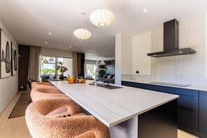 A modern kitchen with a marble countertop, pendant lights, and a built-in stove. - Villa Maya · Rooftop beach access heated pool (Agde)