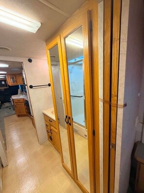 Un pasillo estrecho con una puerta de madera que da a un baño.