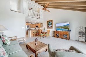 A spacious living area with a high ceiling, a dining set, a television, and a kitchen in the background. - Experience Paradise, 2-Bed Kihei Condo with A/C and New June 2026 Ownership J214 (Kihei)