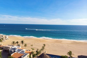 Blick auf einen Strand mit blauem Himmel, feinem Sand und einigen Palmen.