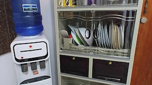 A compact kitchenette with a water dispenser, a microwave, and a glass cabinet containing dishes and utensils. - Bale Magalang (Magalang)