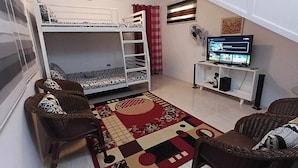 A compact room with a bunk bed, a television, a small desk, and wicker chairs. - Bale Magalang (Magalang)