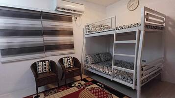 A bunk bed with zebra-patterned bedding, a clock on the wall, and a window with blinds.